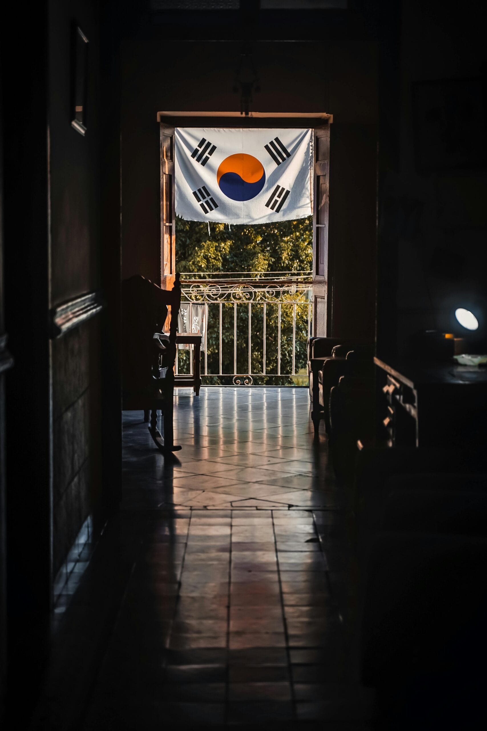 Korean flag visible through a dimly lit doorway, casting warm shadows indoors.
